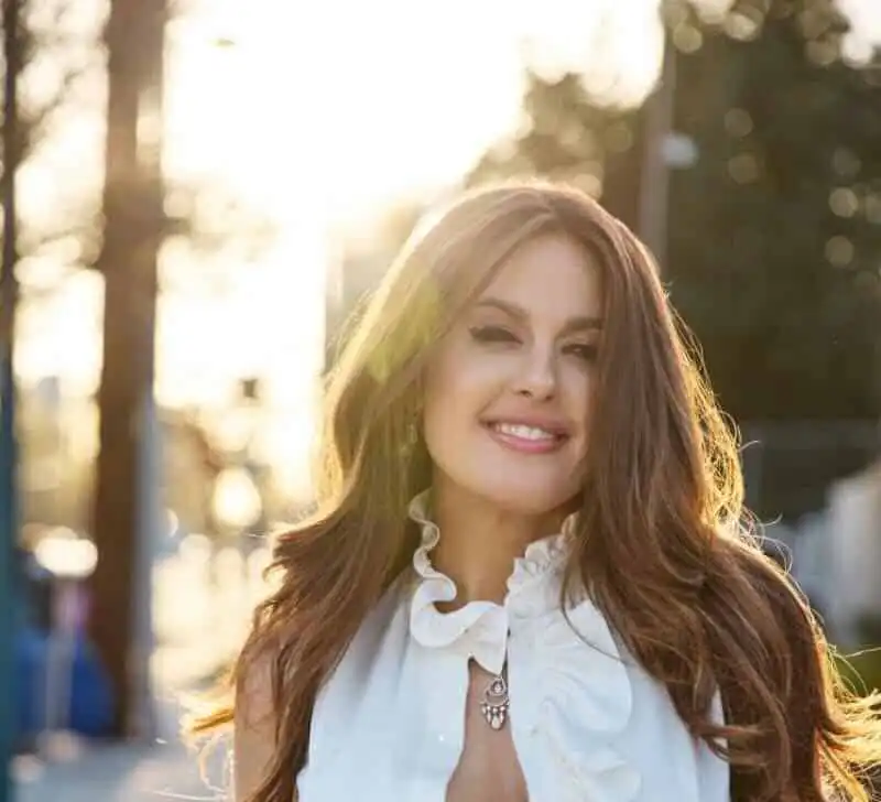 Happy woman smiling outdoors in golden sunlight, natural beauty, warm glow.
