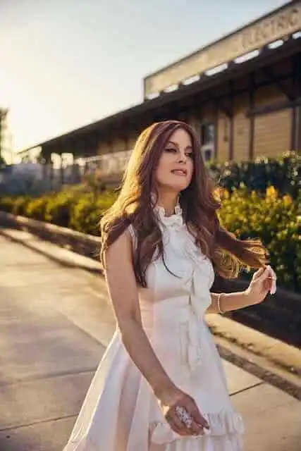 Beautiful woman in white dress at sunset against train station backdrop.