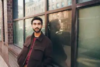 Portrait of a man standing outside near a brick building with reflective windows.