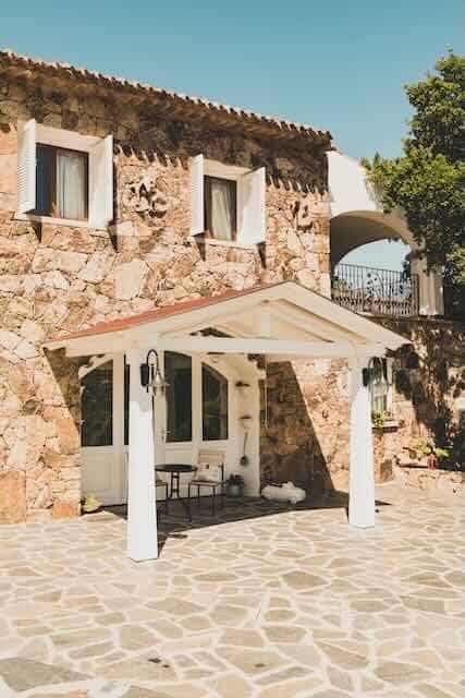 Beautiful stone house with a charming porch and lush greenery.