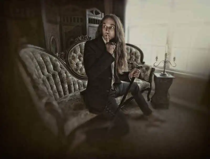 Elegant man in a vintage setting with a cane, pondering thoughtfully on a classic sofa.