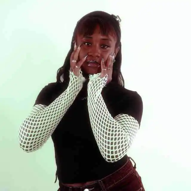 LGBTQ+ woman posing with hands near face, inspiring confidence and self-expression.