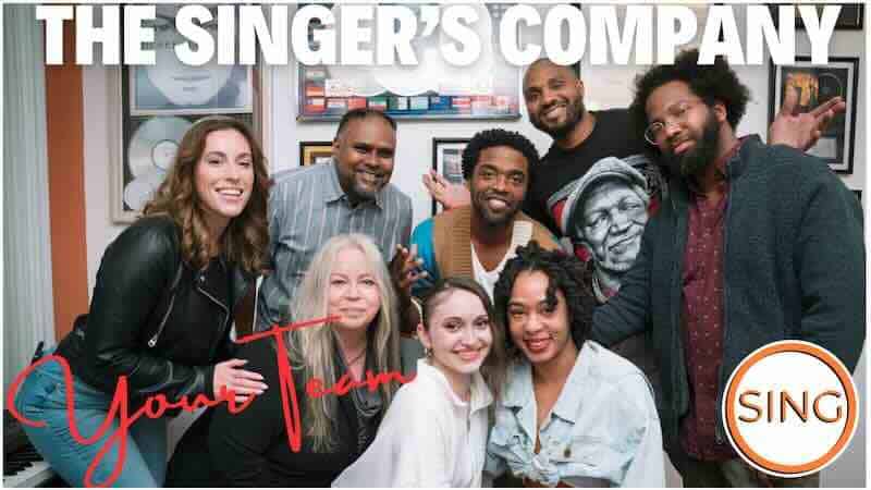 Diverse group of people singing and smiling together in a music studio.