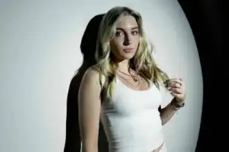 Bold woman portrait with blonde hair and confident expression, studio background.