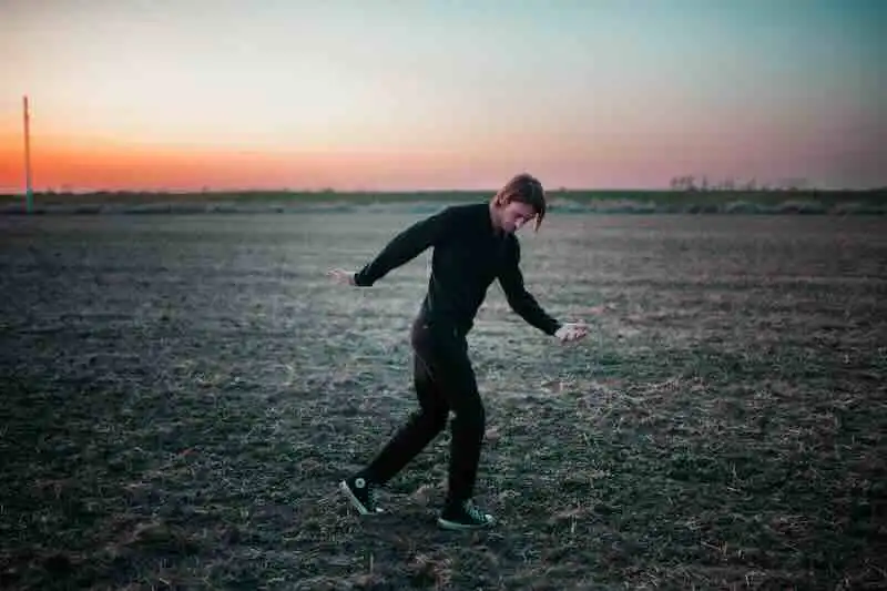 Young person dancing outdoors during sunset, embracing freedom and movement in a vast open landscape.