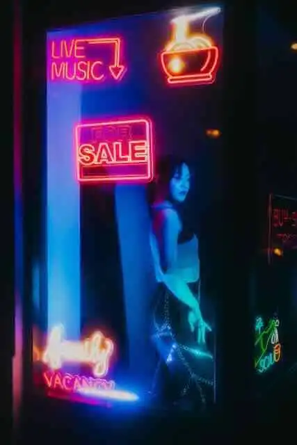 Vivid neon signs advertising live music, a sale, and a cozy coffee cup in a vibrant nightlife scene.