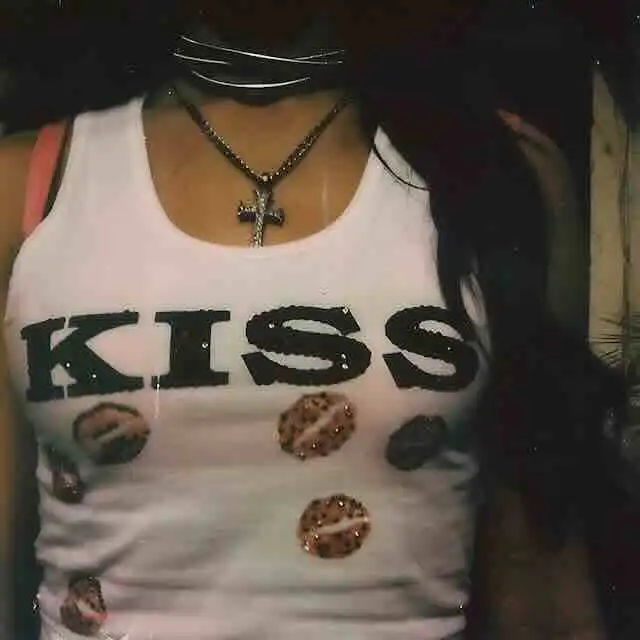 Close-up of KISS logo tank top with lips print, featuring layered necklaces and dark hair.