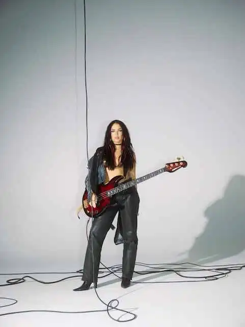 Alternative female musician poses with electric guitar in studio.