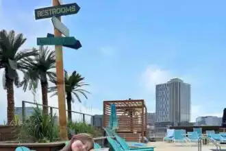 Bright summer scene at rooftop pool with colorful drinks, lounge chairs, and urban skyline.