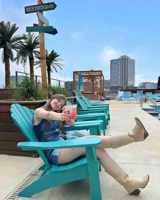 Bright summer scene at rooftop pool with colorful drinks, lounge chairs, and urban skyline.