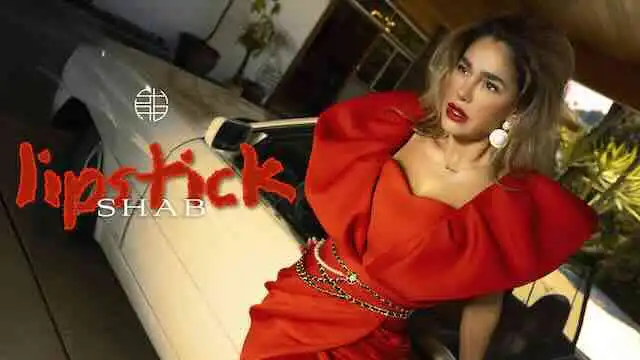 Elegant woman in red dress with bold lipstick and statement earrings, posing near a luxury car.