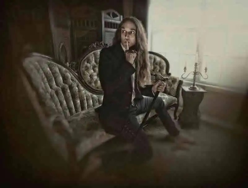 Elegant man in vintage setting, Victorian sofa and candle holder.