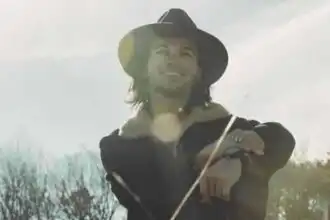 Smiling man in hat enjoying outdoor scenery.