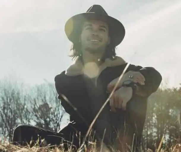 Smiling man in hat enjoying outdoor scenery.