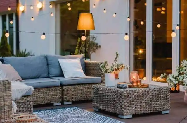Outdoor patio with wicker sofa, coffee table, and ambient lighting for relaxing evenings.