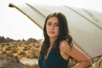 Young woman standing by car in desert landscape.