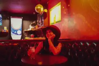 Woman in large hat enjoying night out at cozy bar.