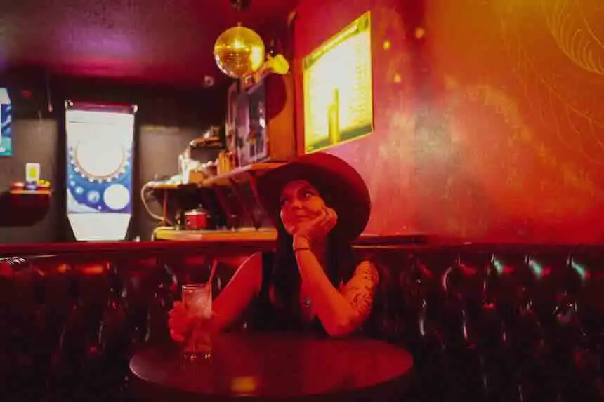 Woman in large hat enjoying night out at cozy bar.
