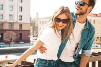 Happy couple in casual clothes, smiling and laughing outside on a city street.