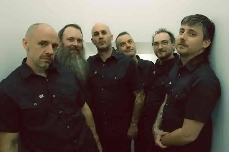 Group of six men in black shirts posing for photo.