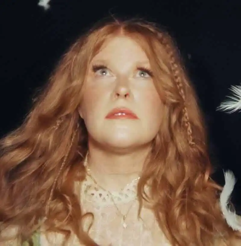 Close-up of a red-haired woman looking upward, with a dreamy and artistic vibe.