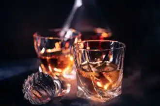 Elegant glasses with rose-colored wine on dark background.