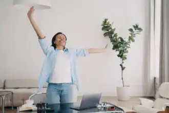 Happy woman enjoying morning stretch in a bright, modern home office.