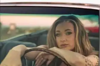 Young woman with tattoos, stylish makeup, sitting in a car, gazing confidently.