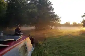 Beautiful sunset scene with a man on a boat beside a river at dawn, showcasing tranquility and nature for divine magazine readers.
