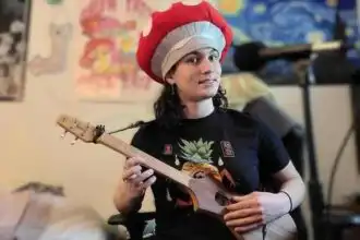 Vibrant image of a woman wearing a whimsical red hat, holding a ukulele, showcasing musical passion.