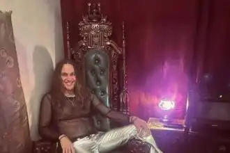 Alternative text showing a woman seated on a regal chair with ornate woodwork and purple lighting.