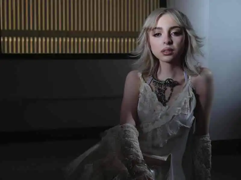 Young woman wearing a vintage lace dress with a statement necklace, soft lighting, modern interior background.