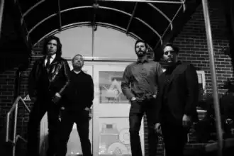 Alt text: Group of four men standing outside a building, posing confidently for a photo.