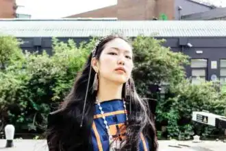 Asian woman wearing stylish tribal-inspired accessories outdoors.