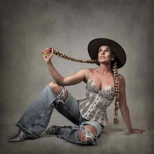 Stylish woman posing with braided hair and wide-brim hat for fashion photoshoot.