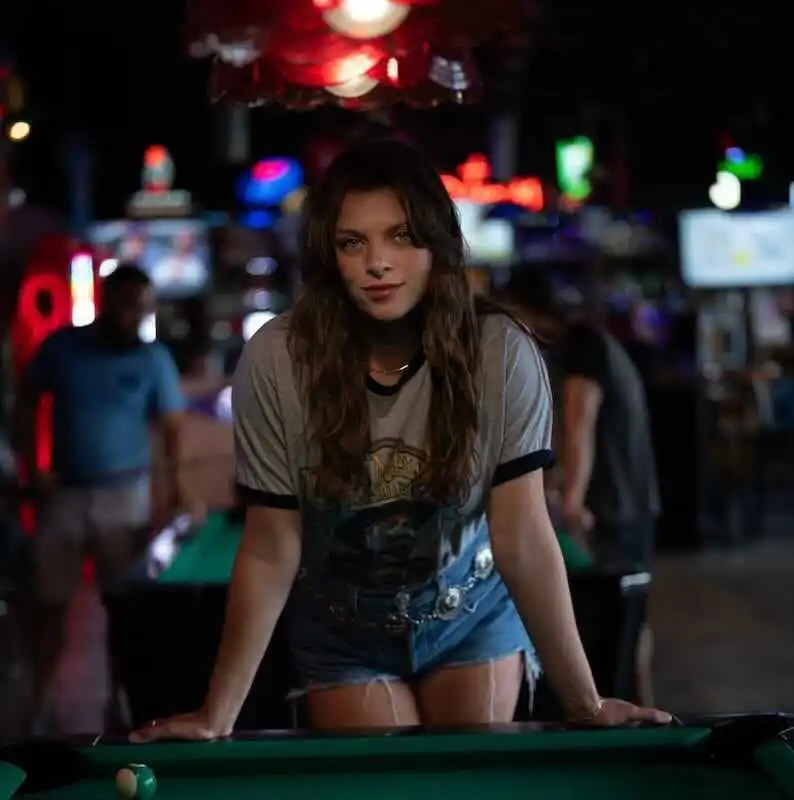 Young woman playing pool in a vibrant bar setting.