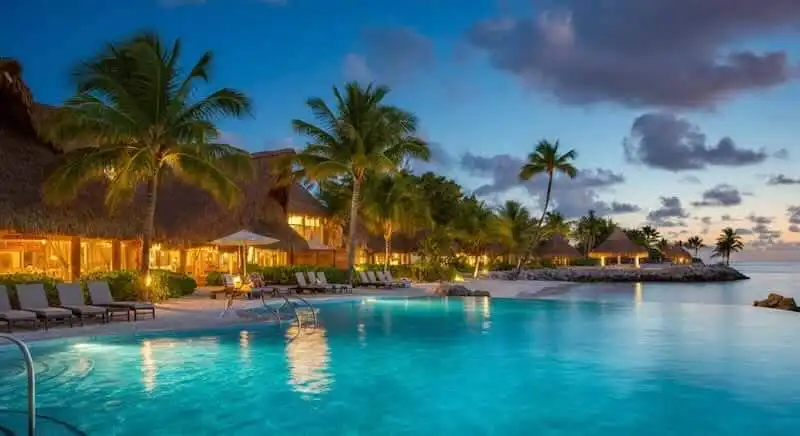 Stunning tropical resort pool with palm trees at sunset, perfect for relaxation and luxury vacations.