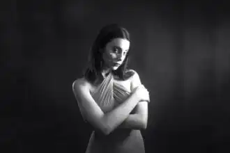 Elegant woman with crossed arms in a classic black-and-white photo, highlighting fashion and timeless beauty.