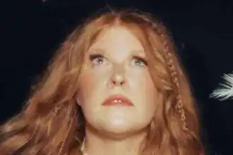 Vivid red-haired woman with flowing hair and intense gaze, mystical and captivating.