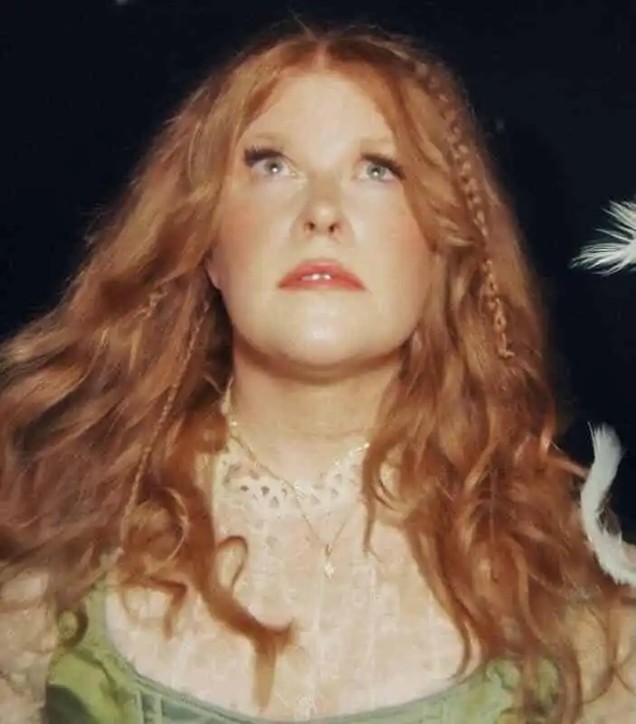 Vivid red-haired woman with flowing hair and intense gaze, mystical and captivating.