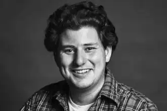 Smiling young man with curly hair in a plaid shirt, portrait in black and white.
