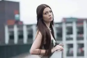 Young woman with long dark hair on rooftop.