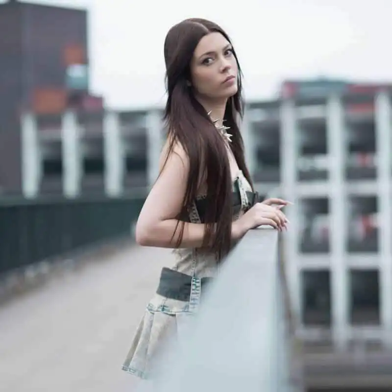 Young woman with long dark hair on rooftop.