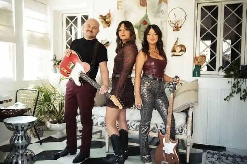 Vibrant LGBTQ+ trio with guitars, celebrating music and diversity in a stylish, welcoming space.