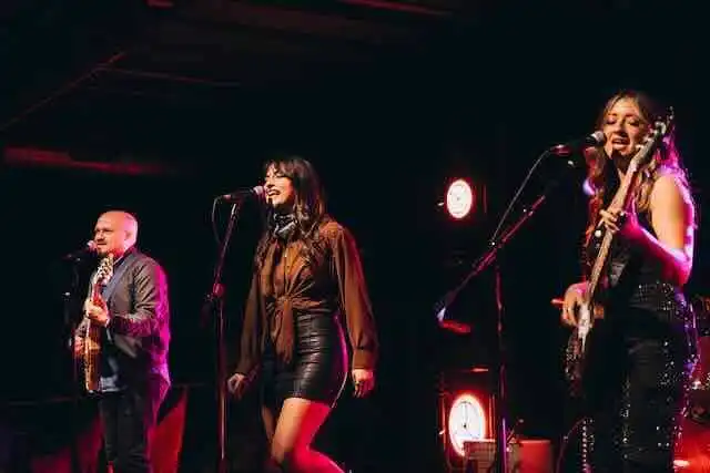Dynamic live music with female vocalists and guitarist at an intimate concert setting.