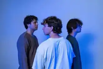 LGBTQ+ young men standing in profile, facing each other against a blue background, emphasizing diversity and identity.