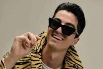 Young man wearing zebra print jacket and sunglasses, smiling confidently.