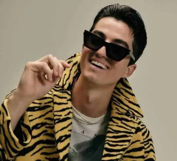 Young man wearing zebra print jacket and sunglasses, smiling confidently.