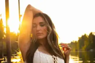 Serene woman enjoying sunset by the river, peaceful mood, natural beauty, summer evening.