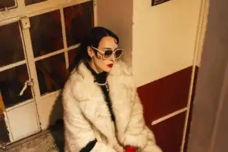 Stylish woman in faux fur coat with zebra print purse and bold accessories, exuding confidence and elegance at Divine Magazine.